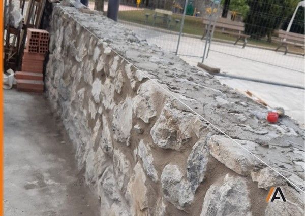 reconstruccion del murete que delimita la zona de juegos en plaza zintururi de Etxebarri, en Bizkaia