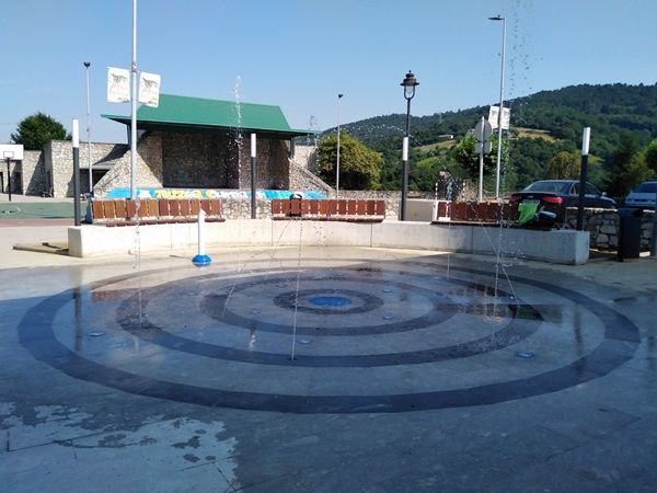 Zona de agua circular con bancos de madera en plaza zintururi